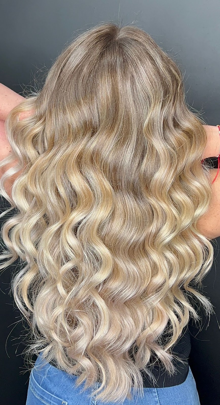 Long blonde wavy hair styled, client result shown from behind