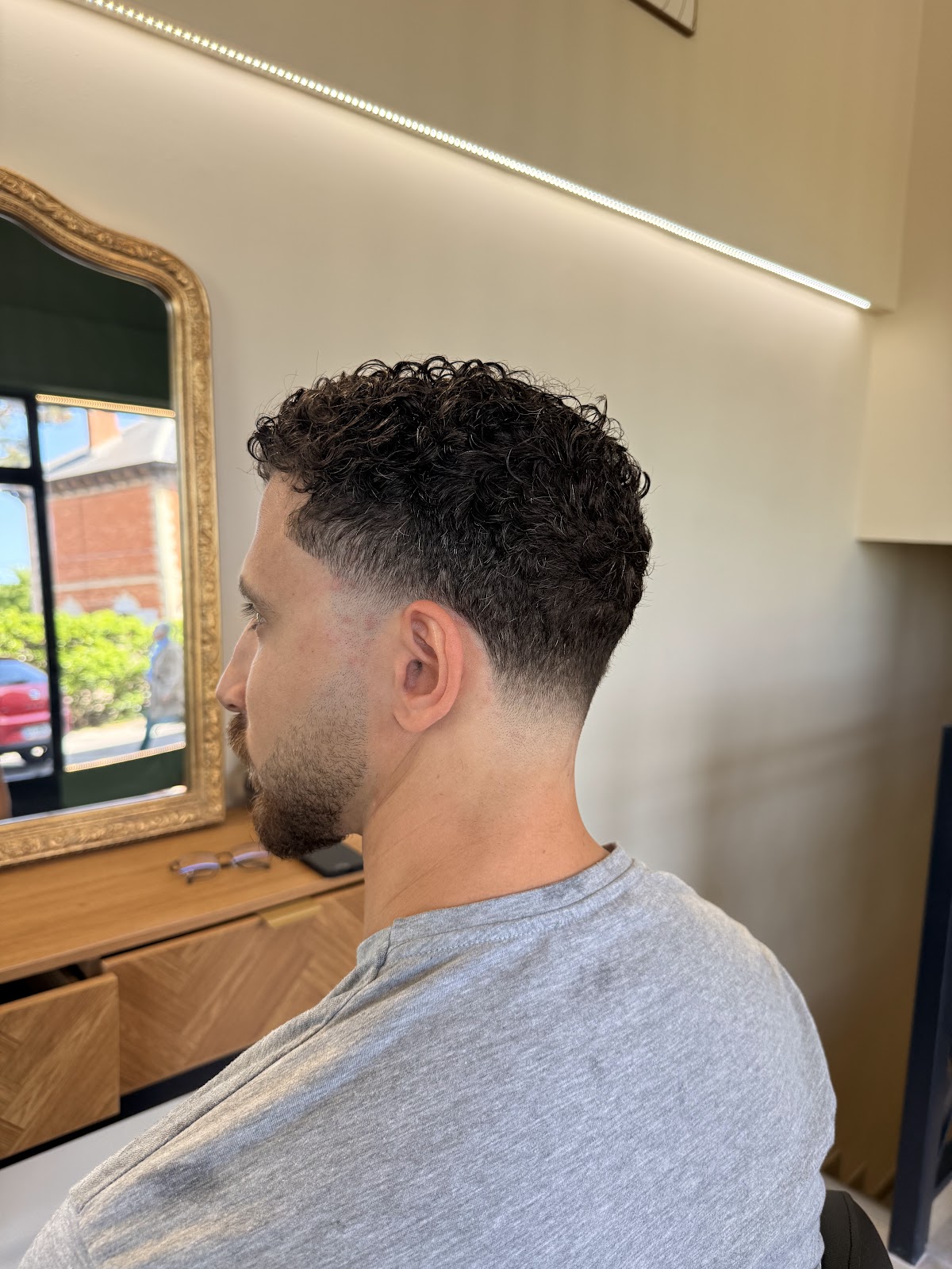 Men's dark curly haircut, styled in profile