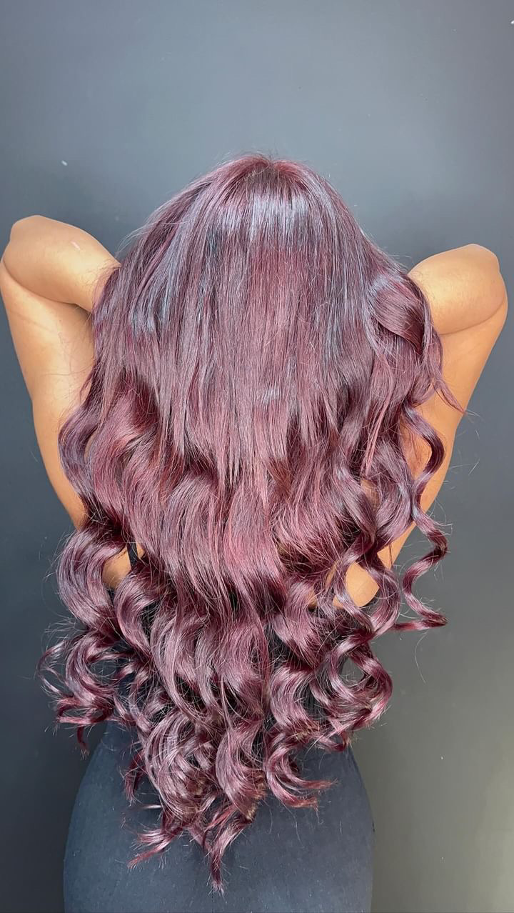 Long wavy burgundy and mauve purple coloured hair styled, shown from behind