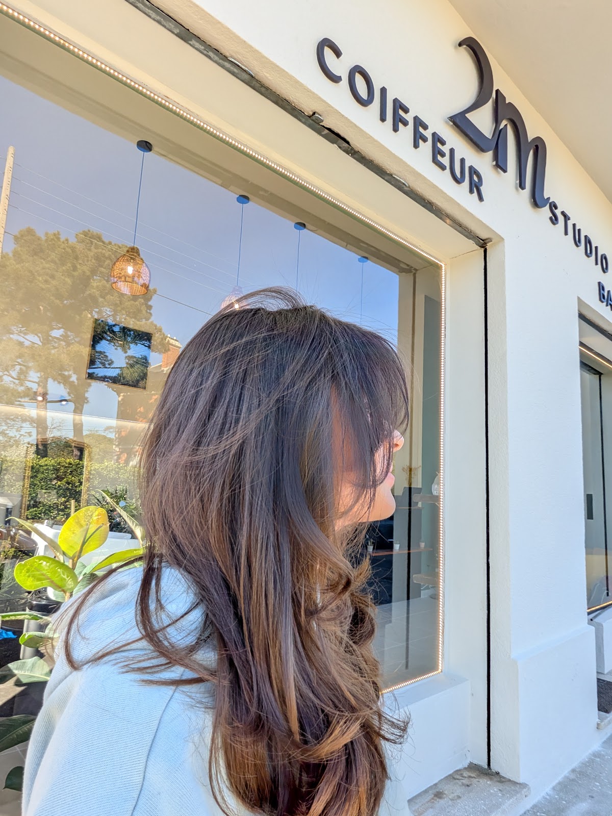 Client from behind outside the storefront, salon signage on the window